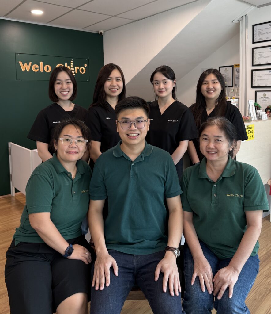The Welo team inside the clinic: three people in green Welo polos seated in front, four in black tops standing behind, with the Welo Chiro sign on the wall